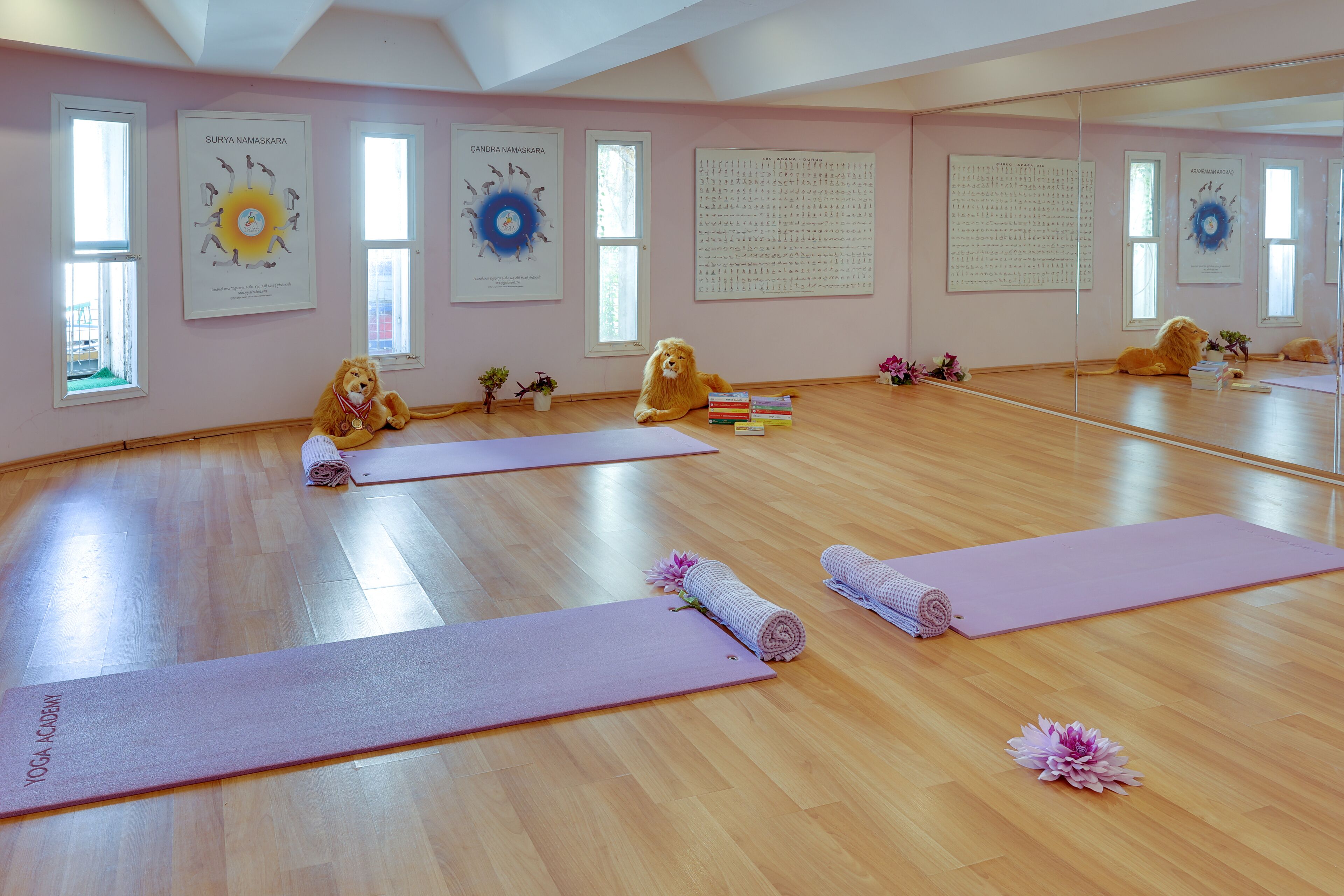 Un studio de yoga doté de planchers en bois, de tapis de yoga et d’une statue de lion.