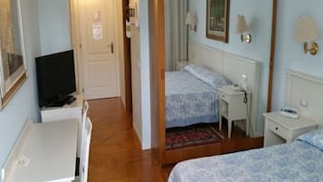 Ett hotellrum med två sängar, ett skrivbord, en tv och en spegel.