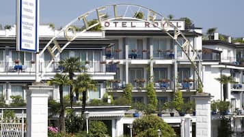 A hotel with a prominent archway sign, multiple balconies with potted plants, and a well-maintained garden area.