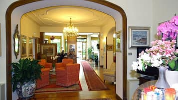 En rummelig lobby med en imponerende lysekrone, et rødt tæppe og en reception.