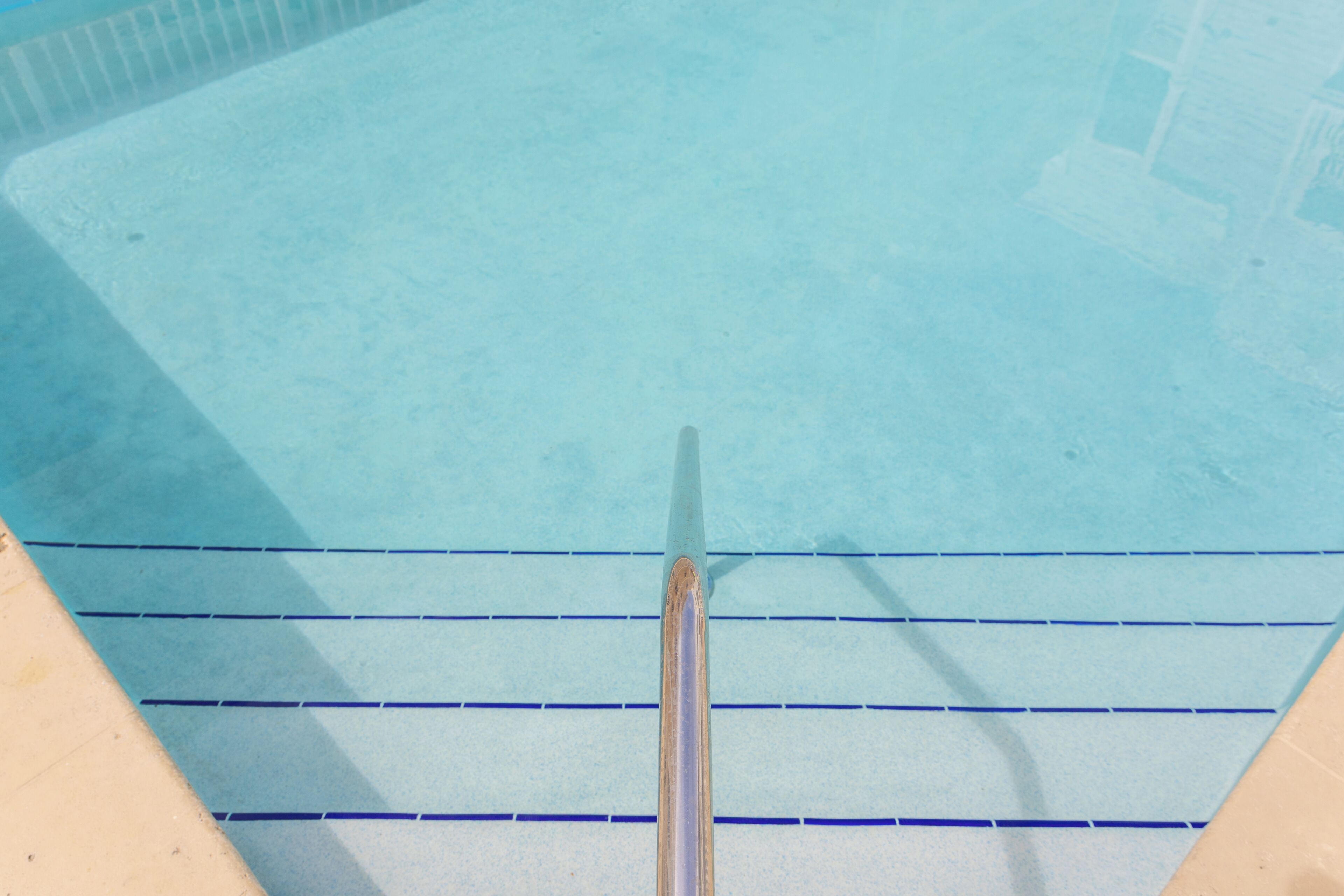 A swimming pool with clear water, a diving board, and tiled steps.