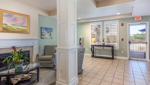 A lobby with a fireplace, seating area, and a glass table with decorative items.