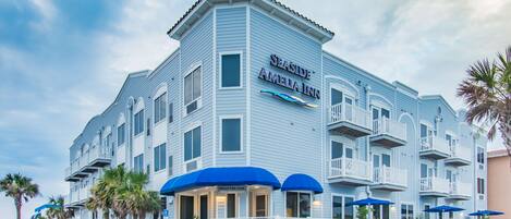 A Seaside Amelia Inn with a registration area, outdoor seating with blue umbrellas, and a balcony on the second floor.