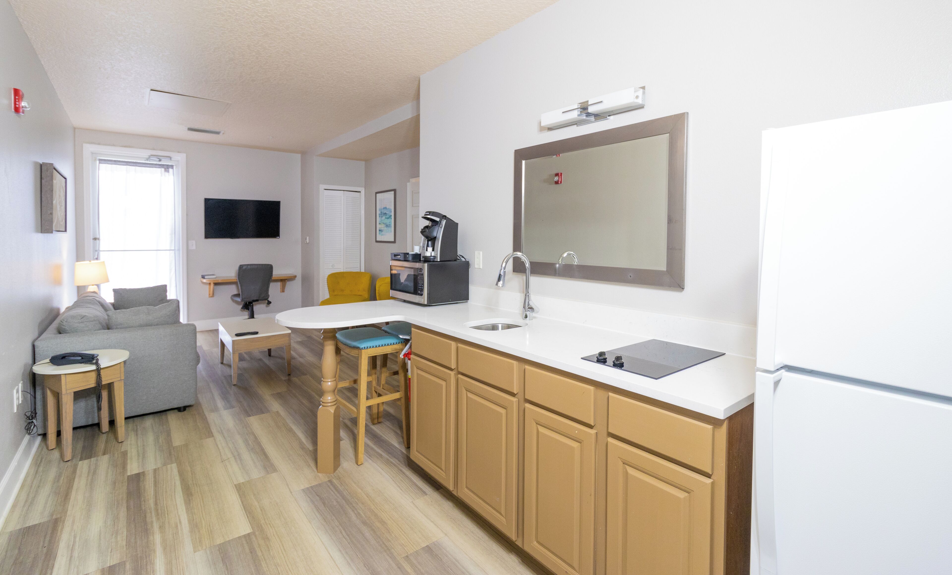 A compact kitchen with a microwave, coffee maker, and sink. There is a dining area with a table and chairs.