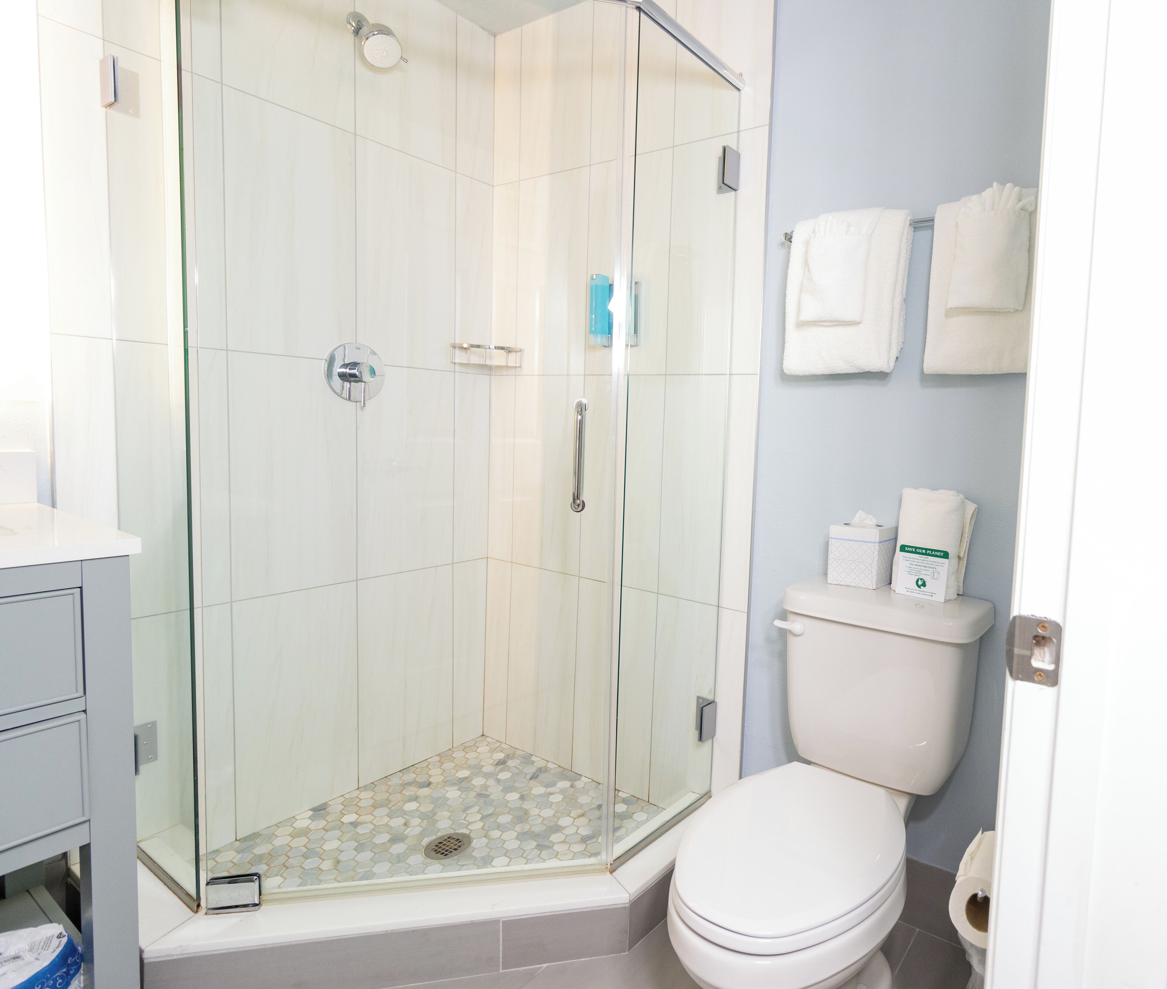 A bathroom with a glass-enclosed shower, a toilet, and a sink.