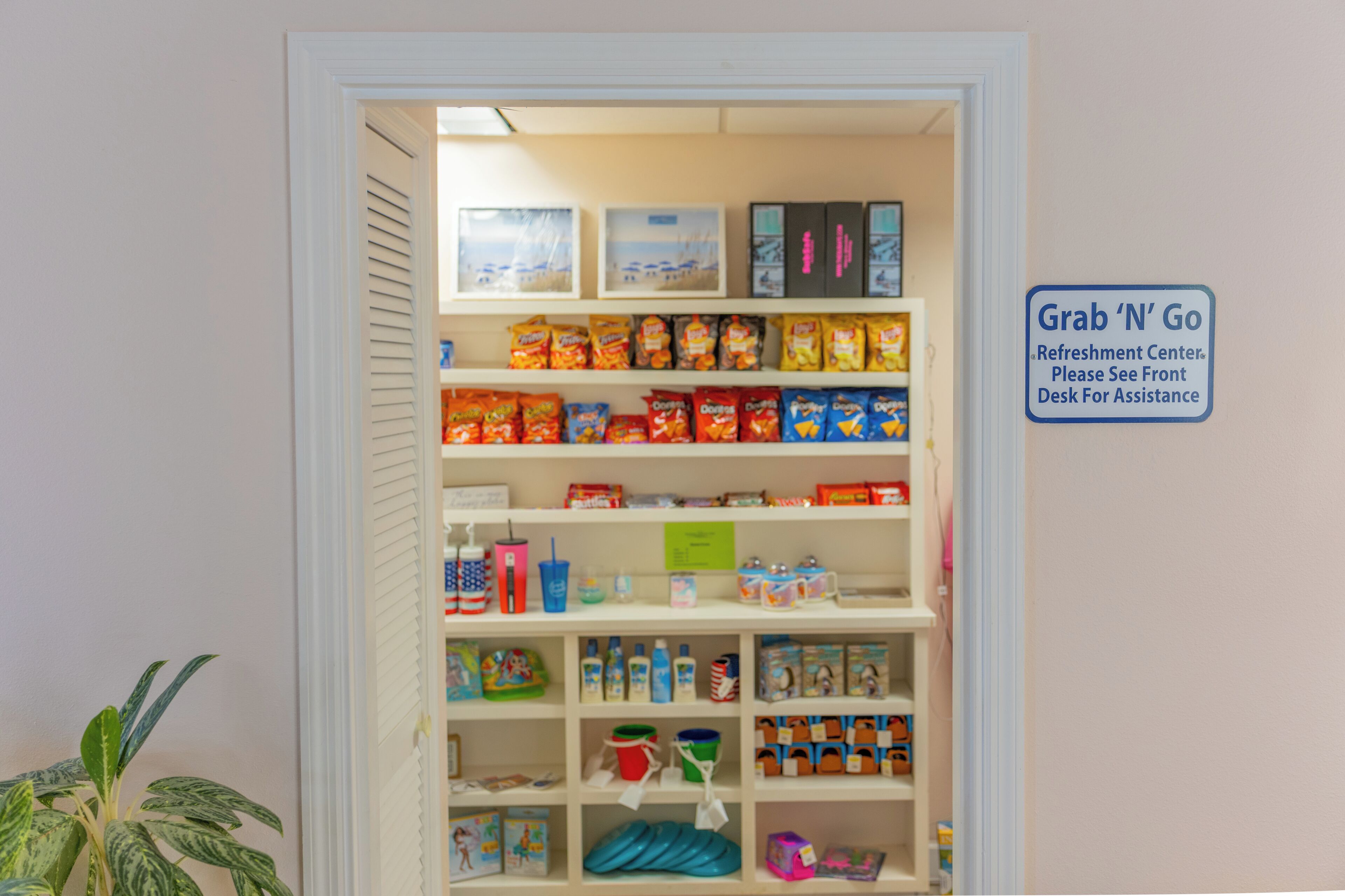 A storage room with shelves stocked with snacks, drinks, and other items. A sign indicates a 'Grab 'N' Go' refreshment center.
