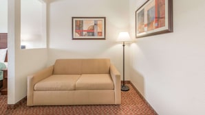 A neutral-colored sofa in a corner, a floor lamp, and two framed abstract paintings on the walls.