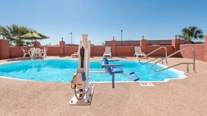 A pool area with a diving board, lounge chairs, and a lifeguard stand.