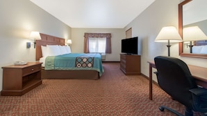 A hotel room with a bed, a desk, a chair, a TV, and a window with curtains.