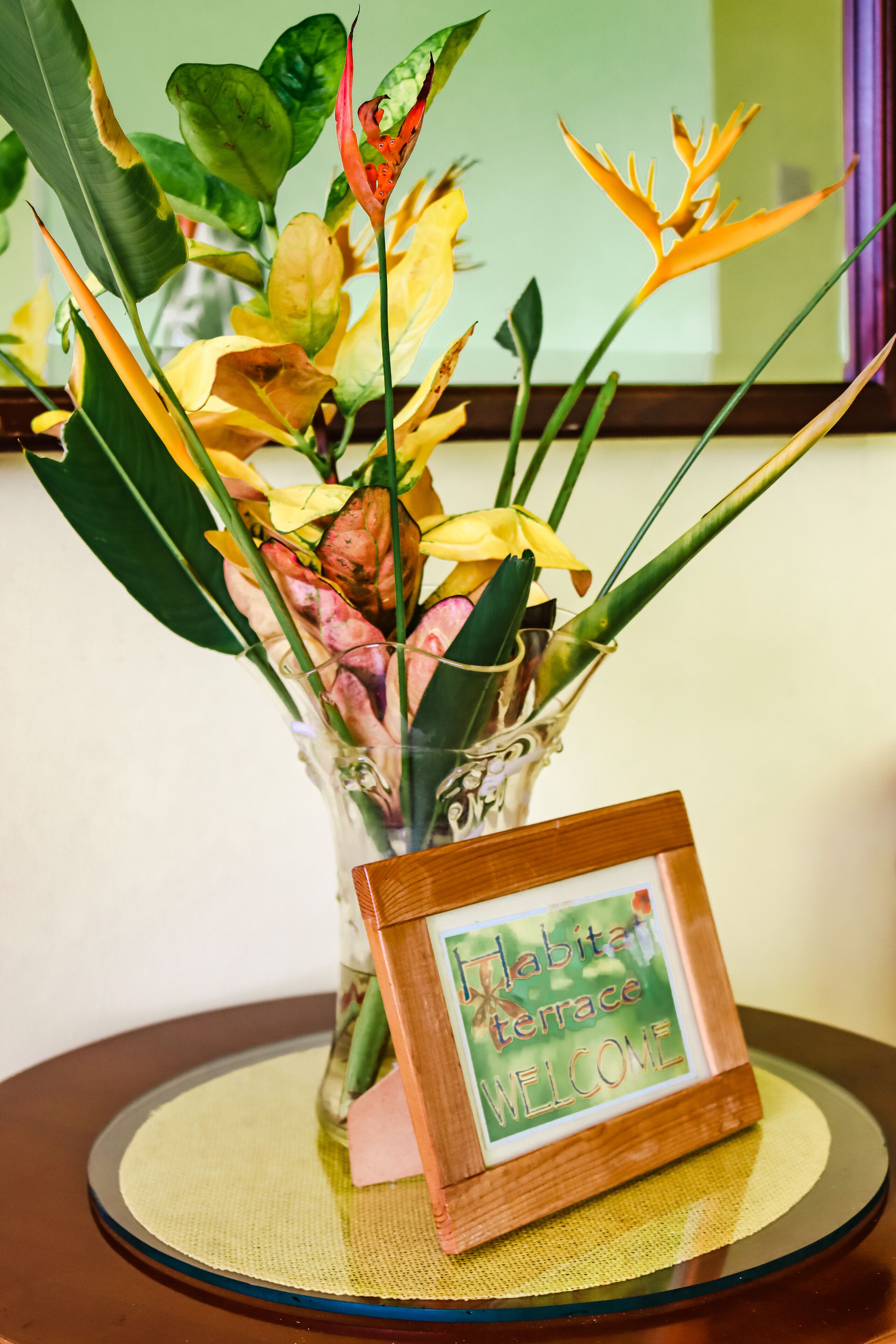 A vase with a variety of flowers and a welcome sign.