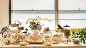 A buffet table with various food items and a large vase of flowers. - Hotel Draconerium (Dronero)
