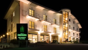 A multi-story hotel with a prominent sign indicating a restaurant and pizzeria. - Hotel Draconerium (Dronero)
