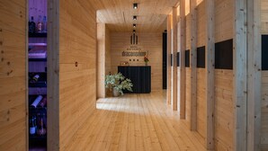 A wooden interior hallway with a reception desk, a potted plant, and shelves with bottles. - Hotel Draconerium (Dronero)