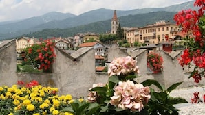 A town with historic buildings, a church, and mountains in the background. - Hotel Draconerium (Dronero)