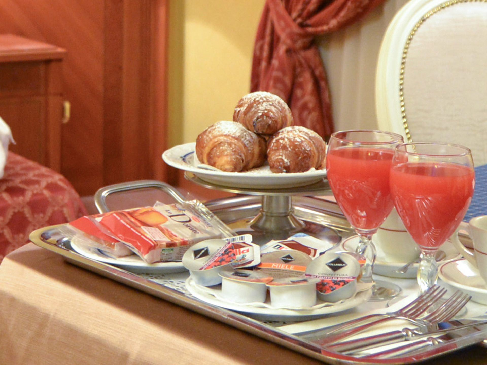A breakfast tray with pastries, juice, and condiments on a table.