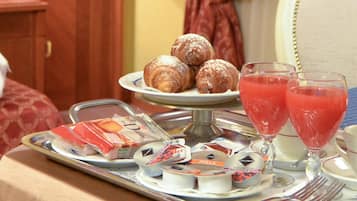 Un plateau de petit-déjeuner avec des viennoiseries, du jus de fruits et des condiments, posé sur une table.