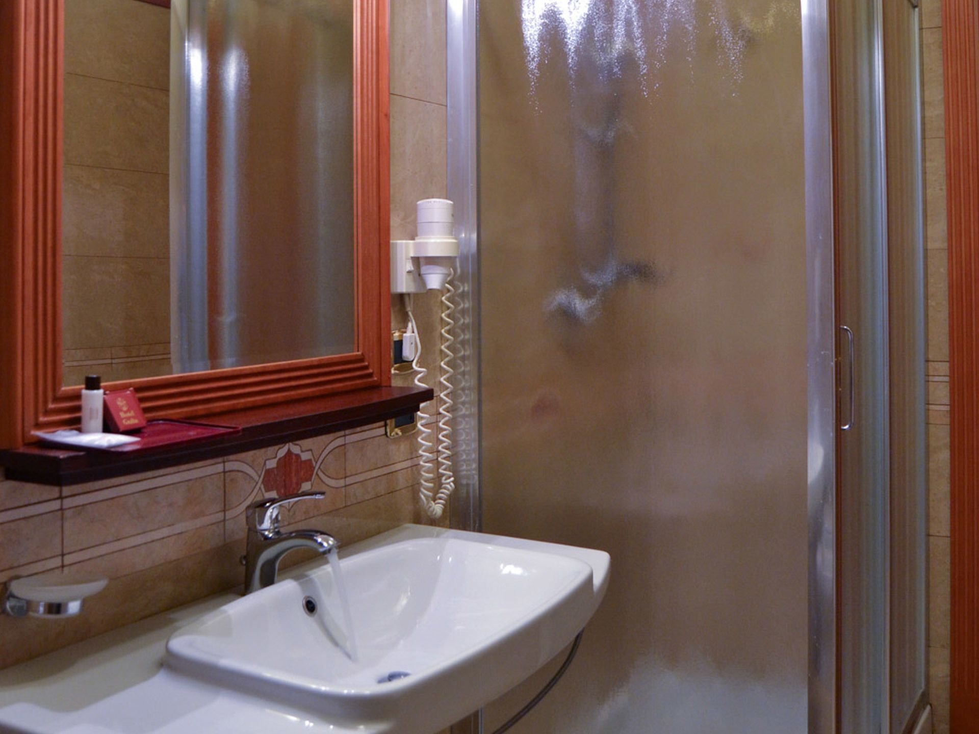 Un bagno con lavandino bianco, uno specchio e una doccia.