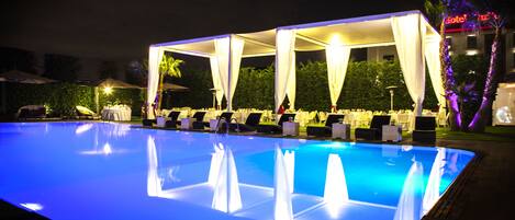 Zona de piscina con un área de estar techada y una pileta.