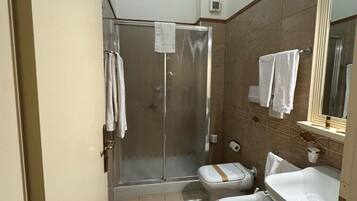 Un baño pequeño y funcional con ducha, inodoro y lavabo.