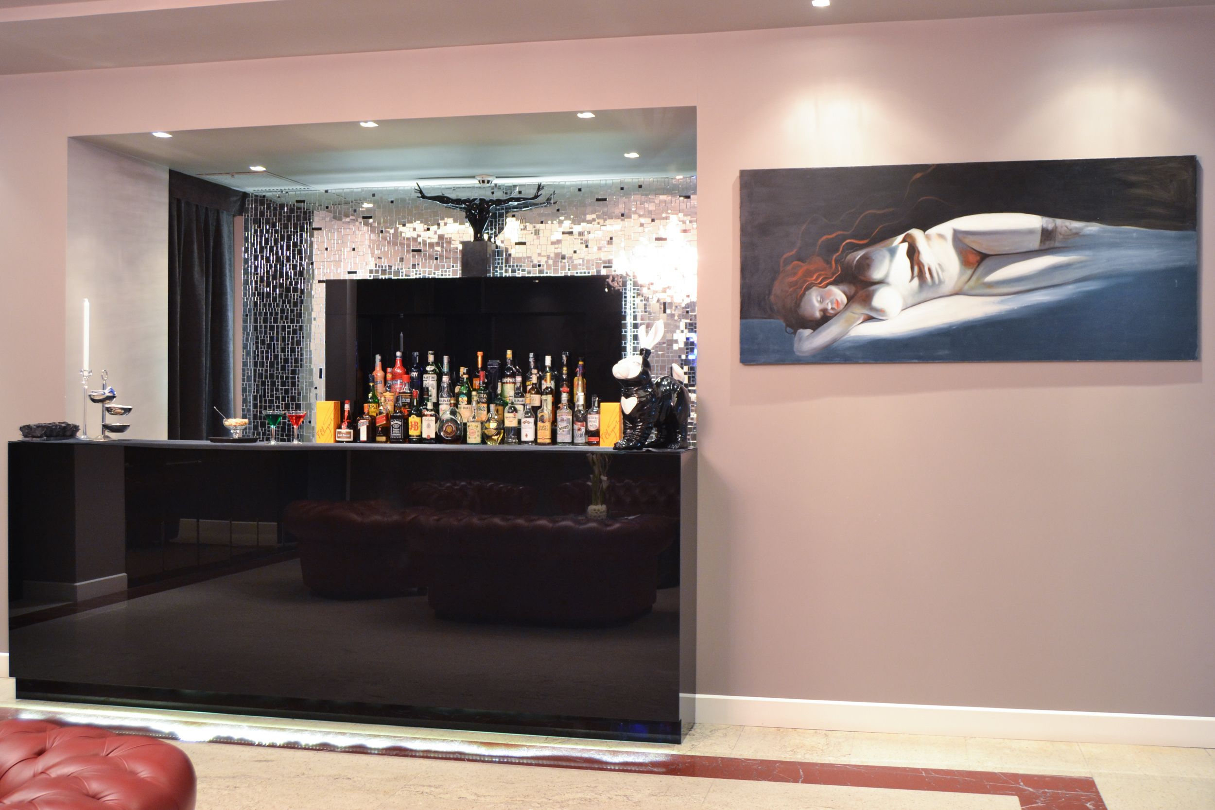 Uma área de bar com uma grande tela de TV, diversos tipos de garrafas e um quadro na parede.