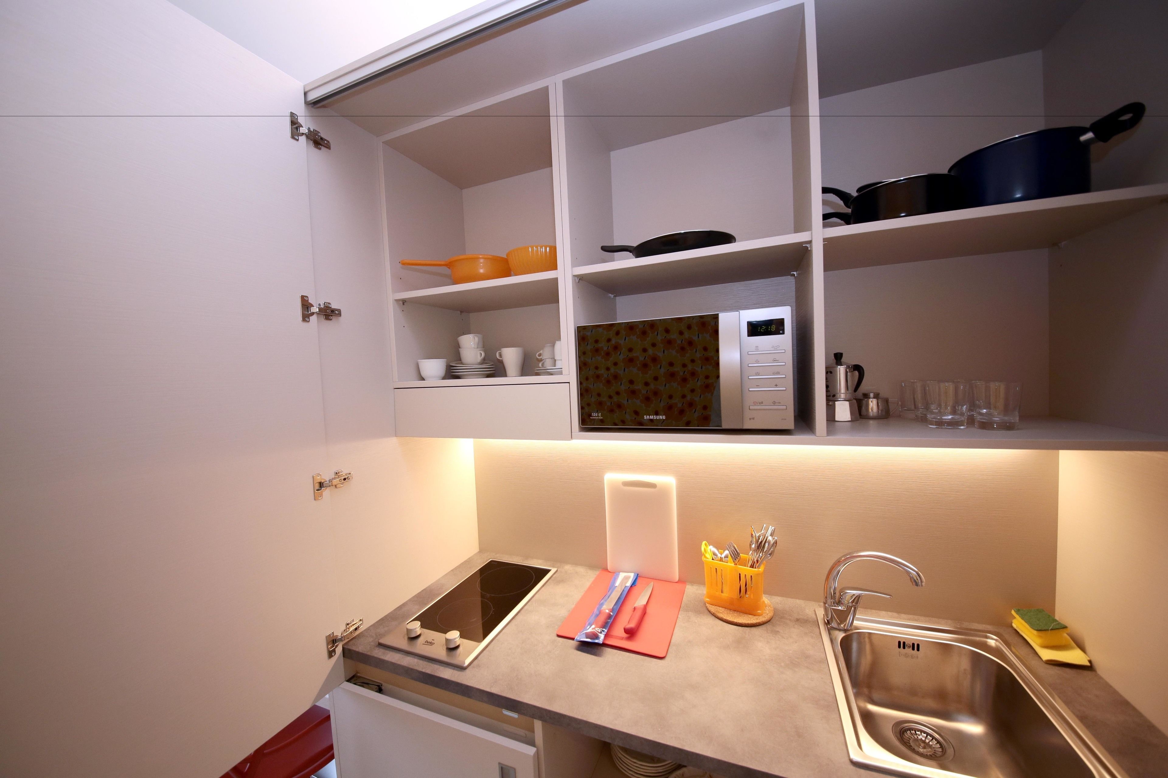 Uma cozinha compacta com fogão embutido, pia e prateleiras acima para armazenamento.