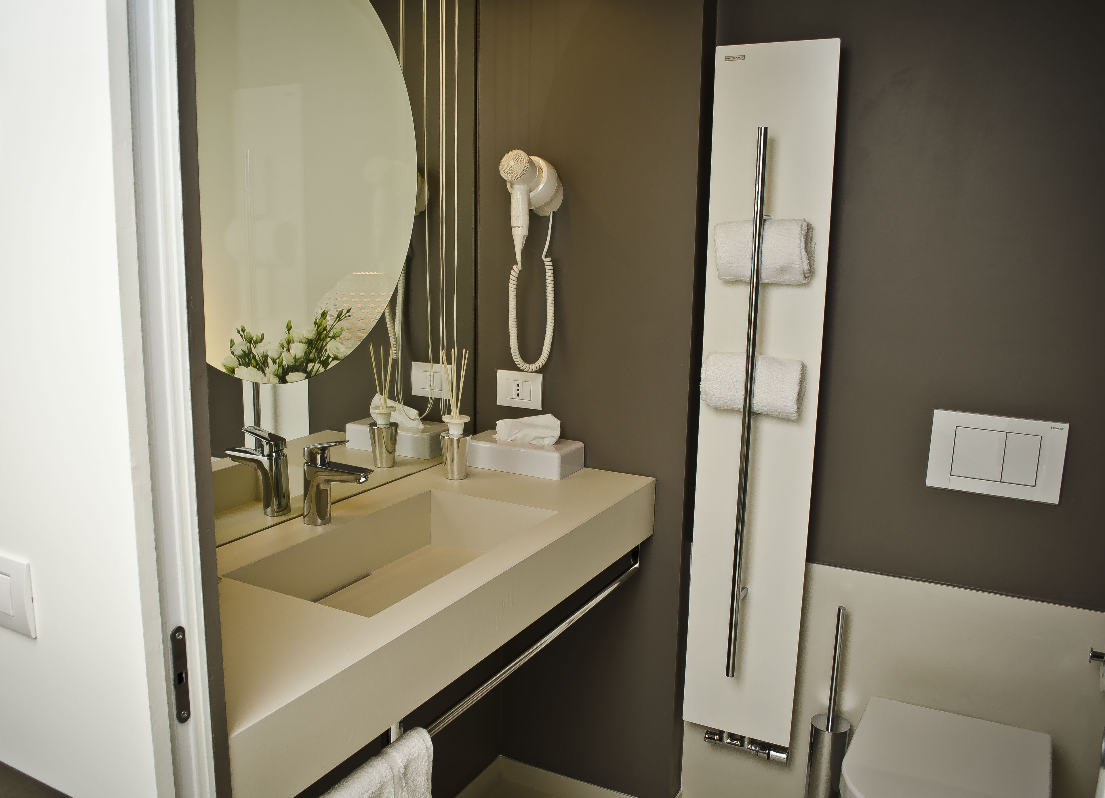 A modern bathroom with a large mirror, a sink, a shower, and a towel rack.