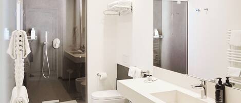 A modern bathroom with a large mirror, two sinks, a toilet, and a shower area.