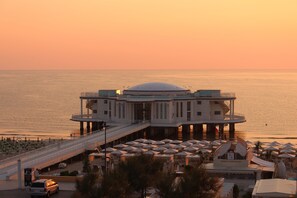 Un hotel con una estructura cúpula central, un espacio de estar al aire libre cubierto y vista al agua.