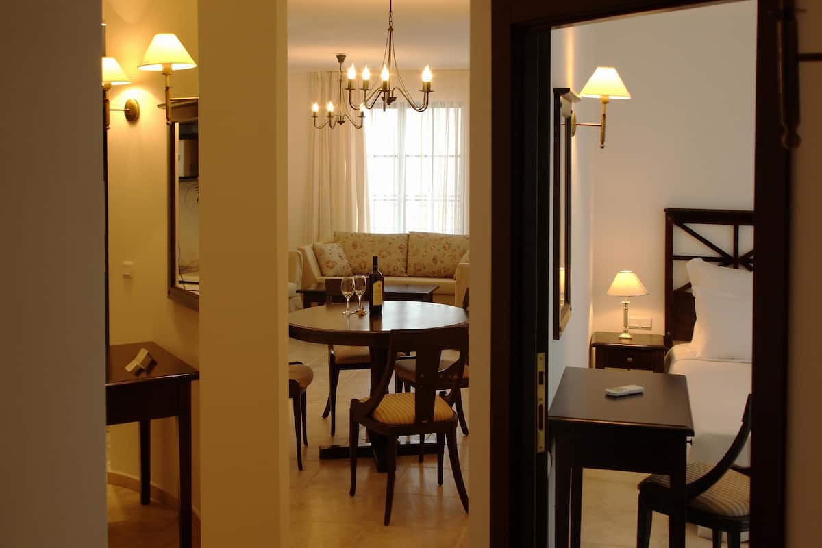 A hotel room with a dining area, a sofa, and a bed.