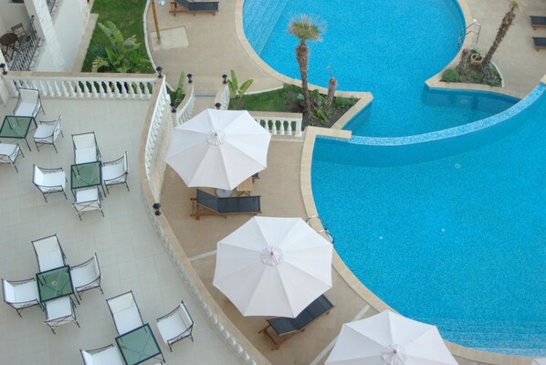 An aerial view of a resort with a swimming pool, outdoor seating, and palm trees. - The Cliff Beach & SPA Hotel (Obzor)