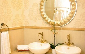 A bathroom with two sinks, a round mirror, and a towel rack. - The Cliff Beach & SPA Hotel (Obzor)