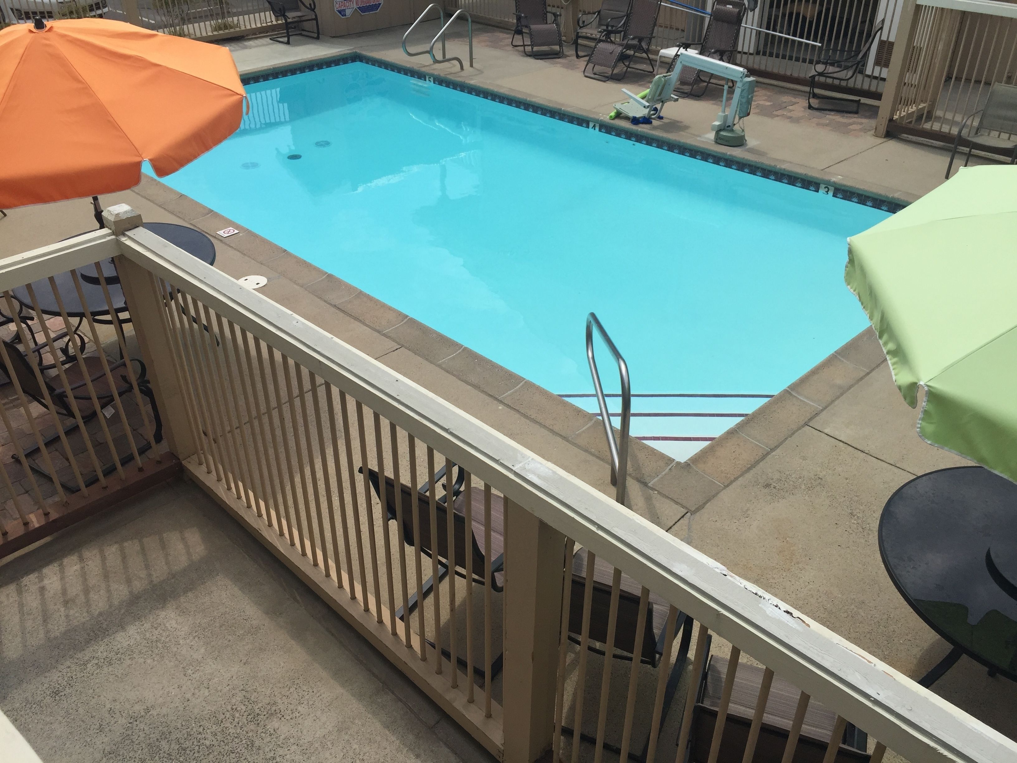 Una piscina rectangular con una escalera metálica y una barandilla de seguridad.