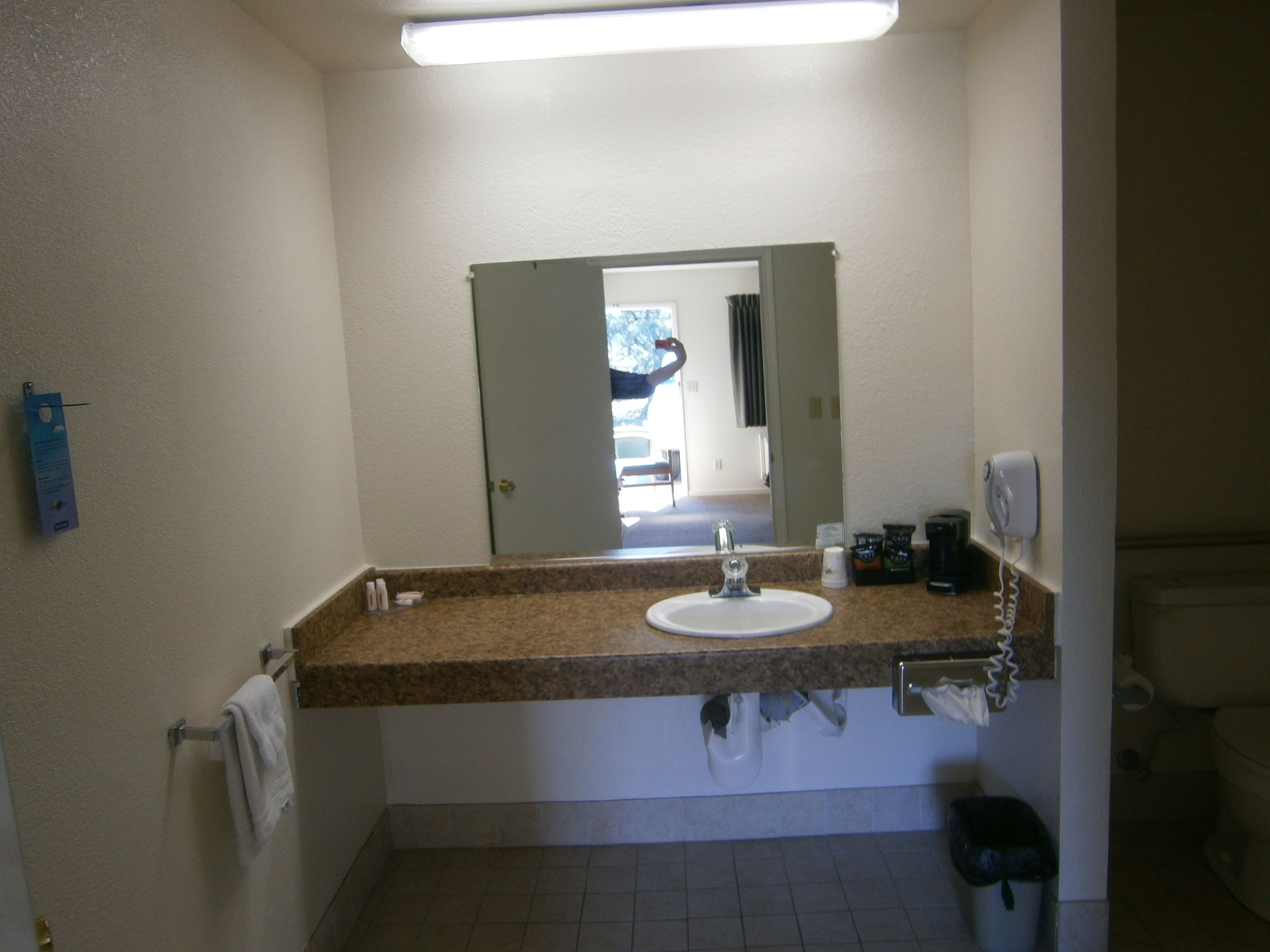 Une salle de bain équipée d’un lavabo, d’un miroir, d’un porte-serviettes et d’une poubelle.