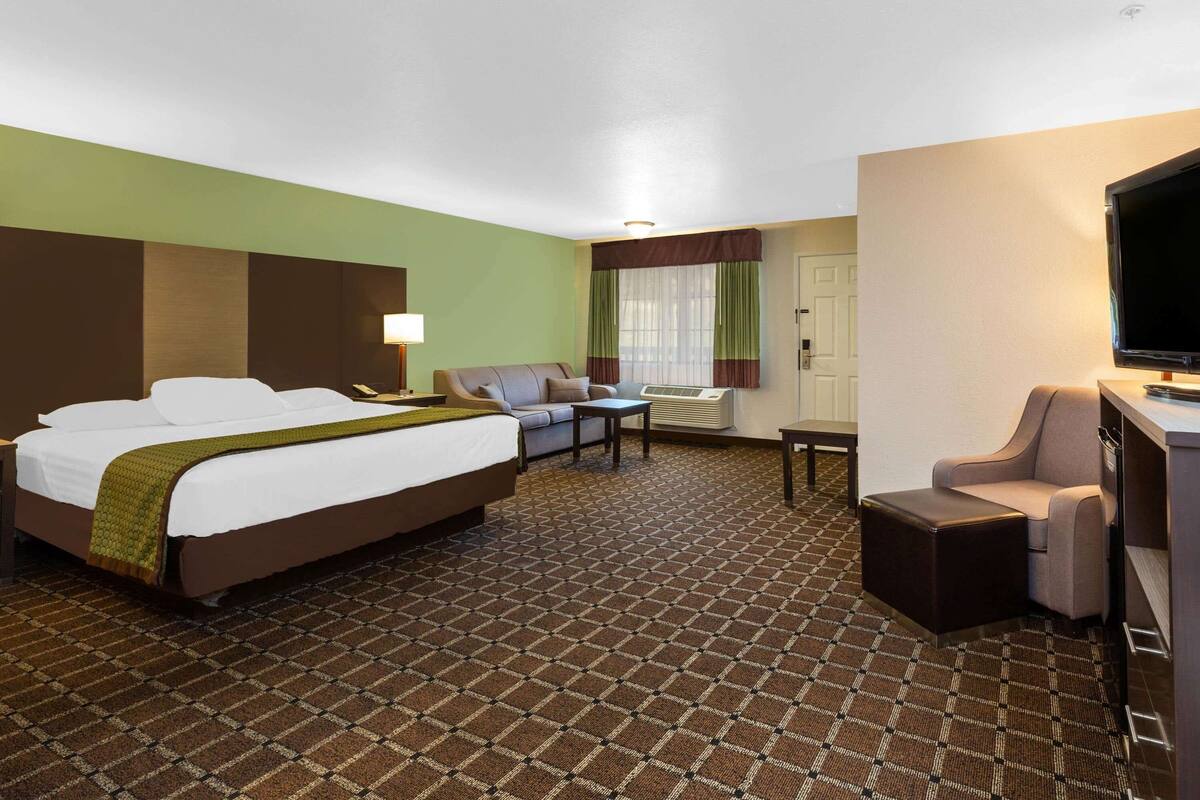 Ein Hotelzimmer mit einem großen Bett, einer Sitzecke, einem Schreibtisch und einem Fernseher.