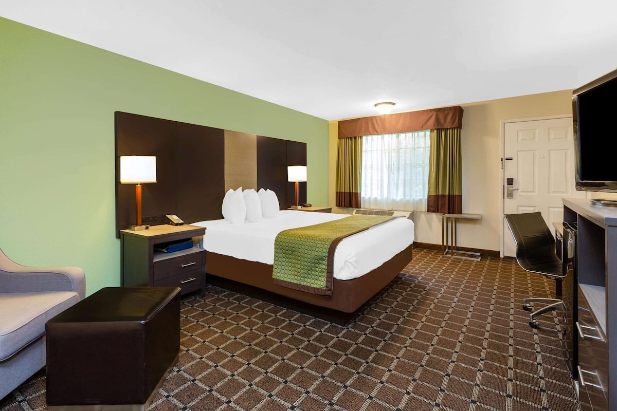 Ein Hotelzimmer mit Bett, Nachttischen, Schreibtisch, Stuhl und Fernseher.