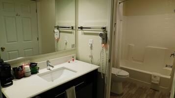 A bathroom with a white sink, a mirror, a toilet, and a shower.