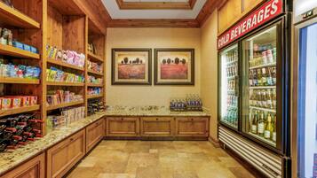 A kitchen area with wooden cabinets, a marble countertop, and a refrigerator labeled "COLD BEVERAGES".