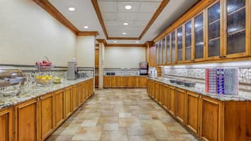 A spacious kitchen with wooden cabinets, a tiled floor, and a central island with a sink and countertop.