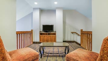 A hotel room with a TV, wooden furniture, and a patterned carpet.