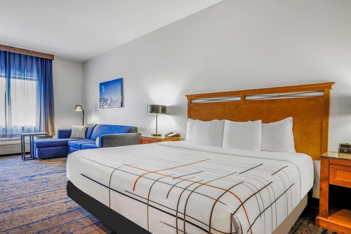 Een hotelkamer met een groot bed, een bank, een bureau en een lamp.