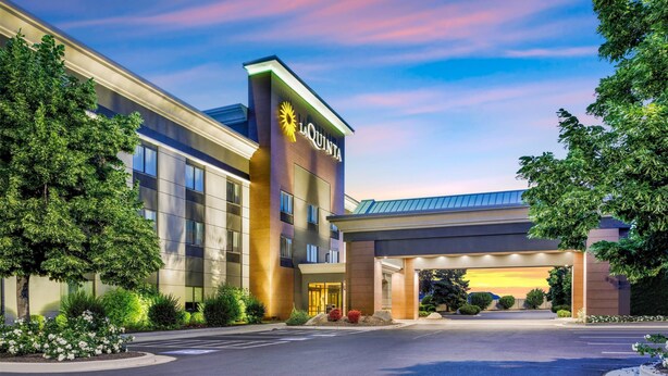 A modern hotel with a prominent 'La Quinta' sign, a covered entrance, and well-maintained landscaping.