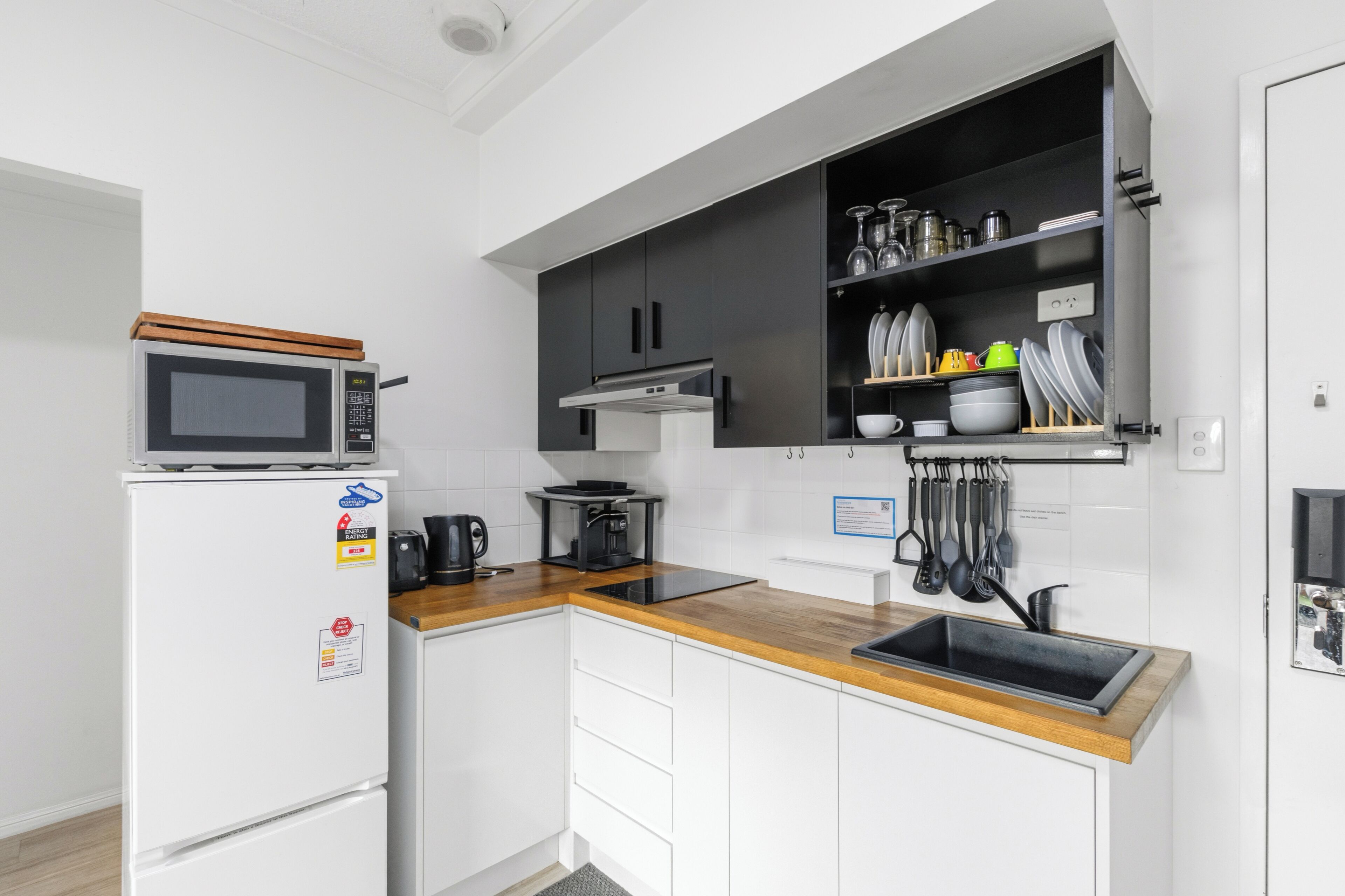 A compact kitchen with a microwave, coffee maker, and a wooden countertop.