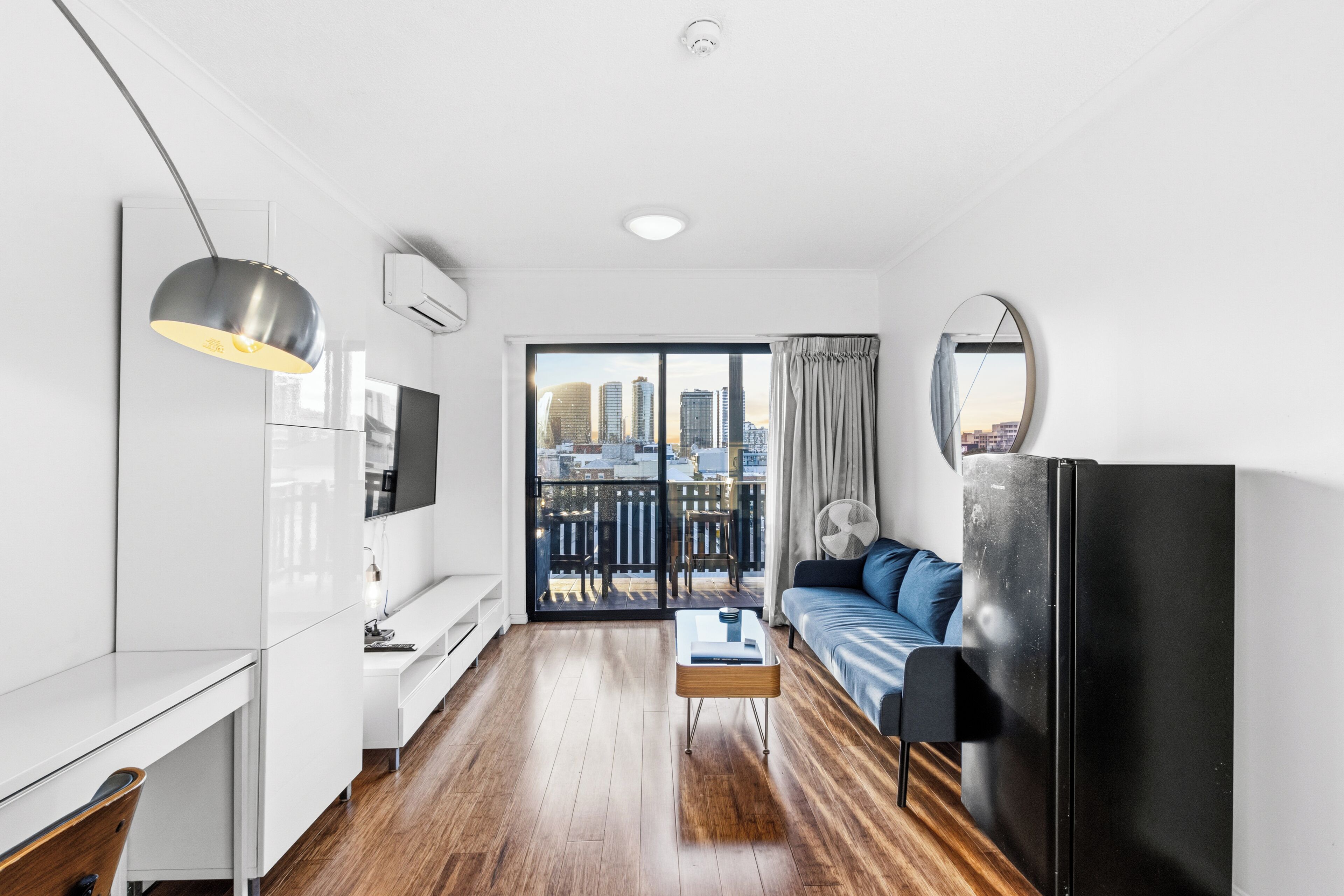 A modern apartment with a city view, a dining area, a sofa, and a TV.