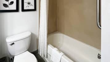 Un baño con inodoro, bañera y dos cuadros en la pared.