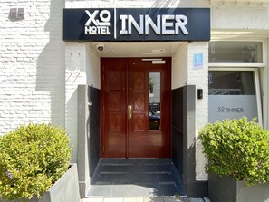 La entrada al hotel XO Inner, con una puerta de madera oscura y un letrero arriba.