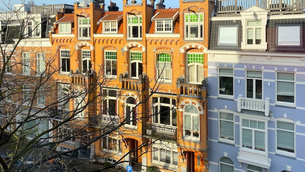 Una hilera de edificios de varios pisos con estilos arquitectónicos diferentes, incluyendo fachadas de ladrillo y marcos de ventanas blancos.
