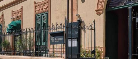 A building facade with a sign reading 'Kalamon Restaurant,' a black gate, and a green awning.