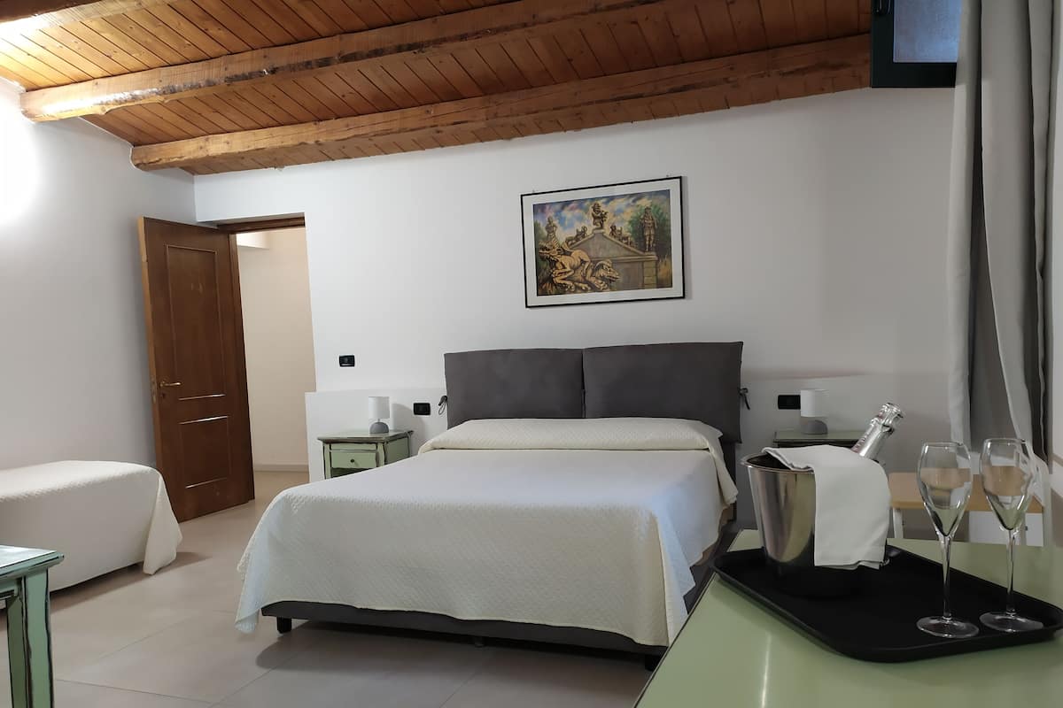 Un dormitorio con cama, mesitas de noche, un cuadro y una bandeja con vasos.