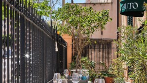 An outdoor dining area with tables set for two, surrounded by potted plants and a decorative fence. - Villa Scaduto Residence (Bagheria)