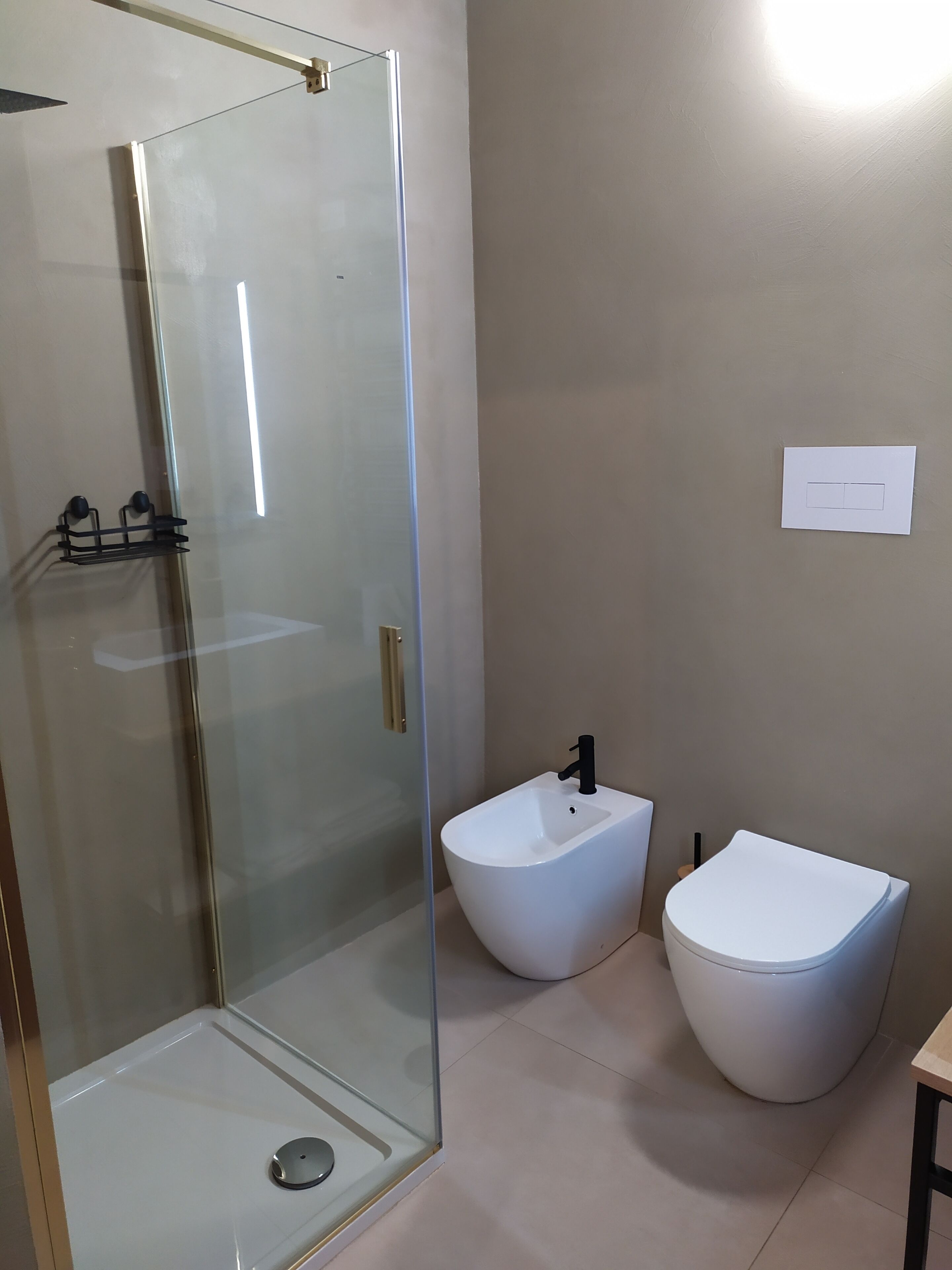 A modern bathroom with a glass-enclosed shower, a bidet, and a toilet.
